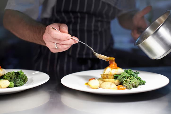 Chef plating a dish during professional food service.